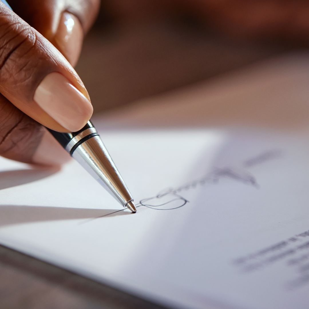 Hand signing a contract with a pen
