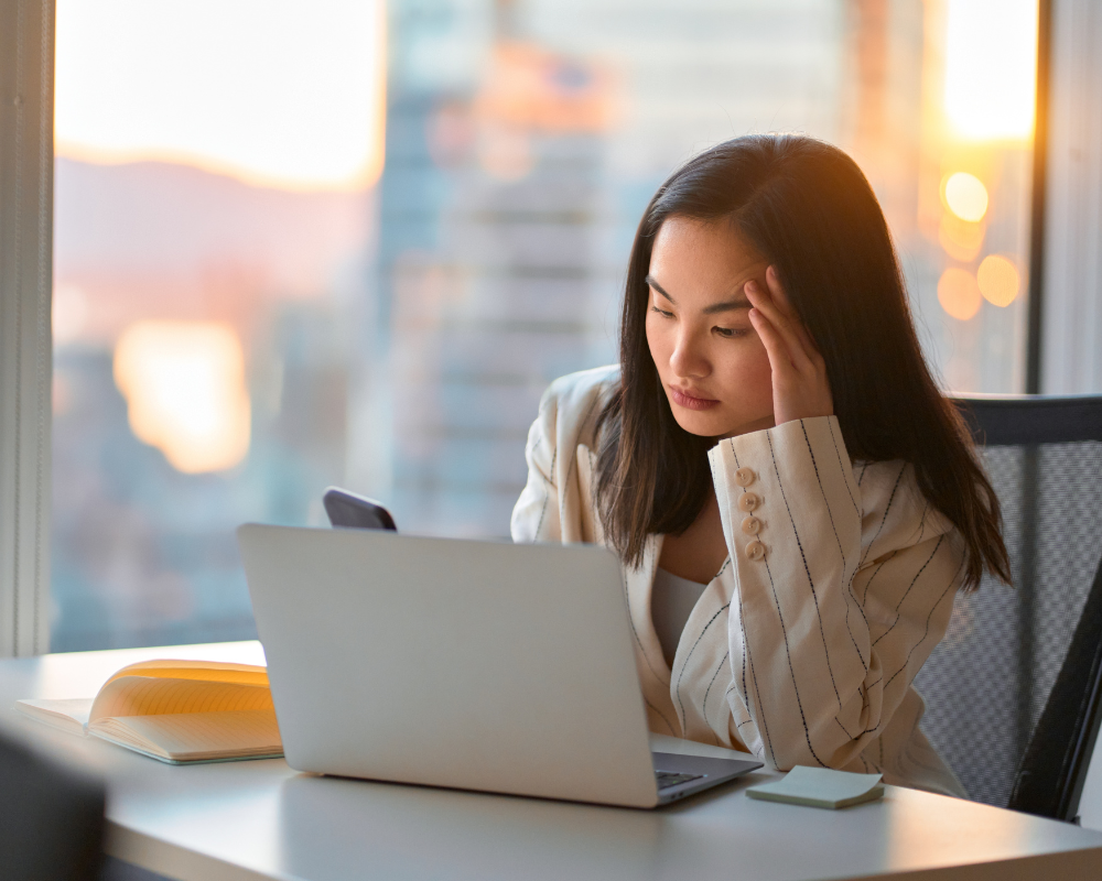 Stressed woman holding her head while working at a laptop