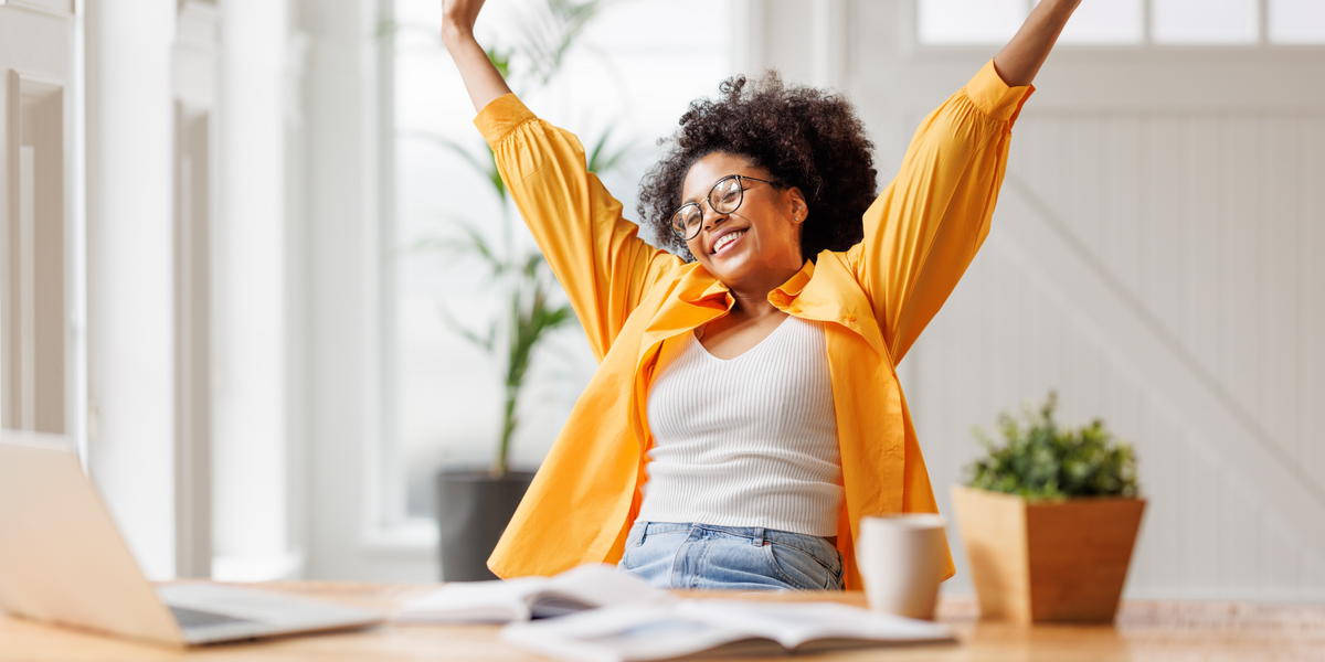 Woman raising her arms in celebration at her desk